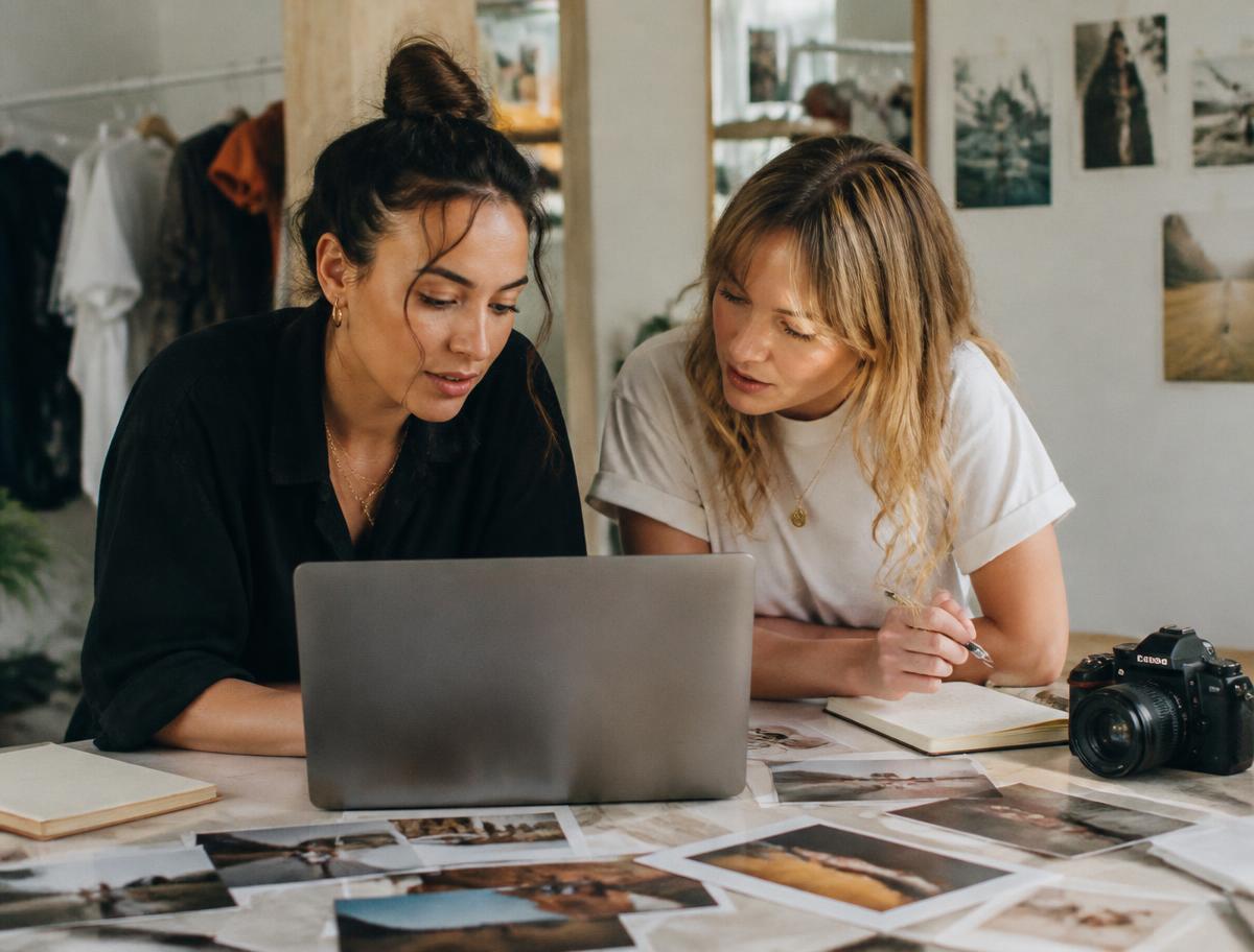 Two collaborators reviewing printed photos and a laptop during a content day